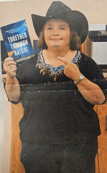 woman dressed in black holding a book and pointing to it