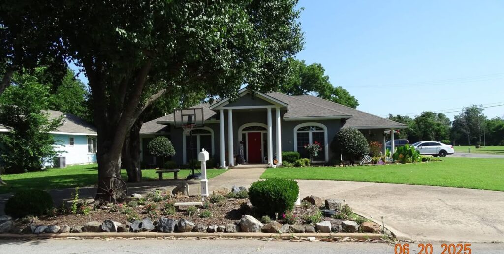 Well-kept yard with lush green grass, blooming flowers, and manicured landscaping in front of a charming Walters home.
