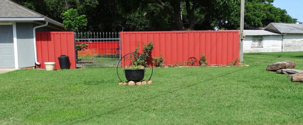Well-kept yard with lush green grass, blooming flowers, and manicured landscaping in front of a charming Walters home.