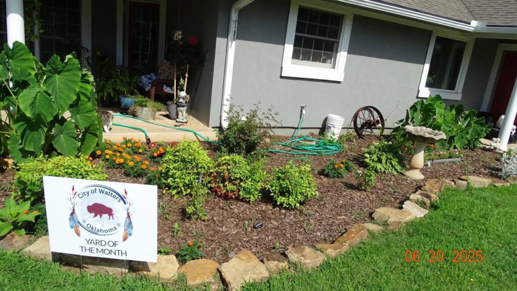 Well-kept yard with lush green grass, blooming flowers, and manicured landscaping in front of a charming Walters home.